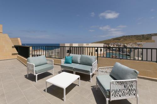 a balcony with chairs and a table and the ocean at Jacuzzi Penthouse with Large Terrace & Views in Marsalforn