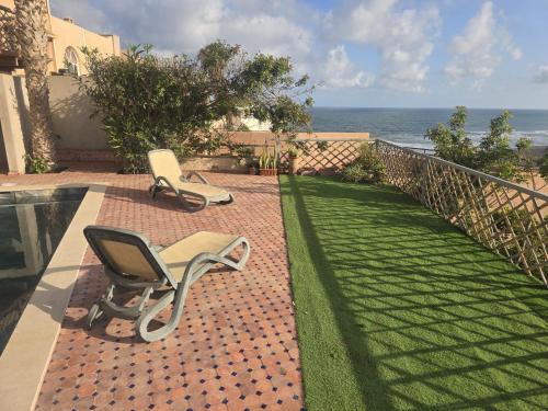 two chairs sitting on a brick path next to a swimming pool at Ocean View 6 bed Villa and Pool in Mirleft