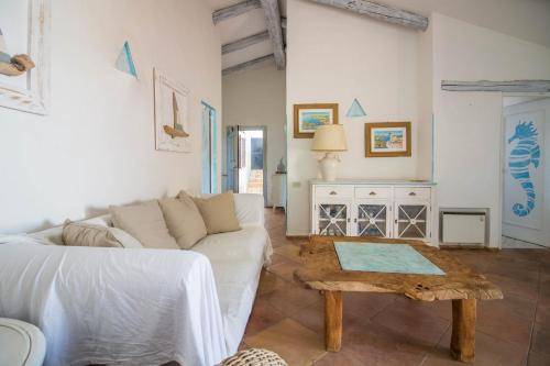a living room with a white couch and a table at GuestHost - Sea View Flat with Veranda and Pool in Liscia di Vacca