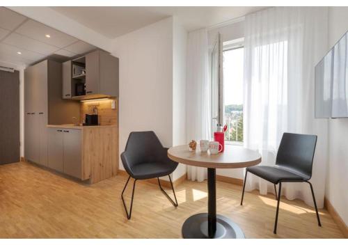 a room with a table and two chairs and a kitchen at Brera Stuttgart in Stuttgart