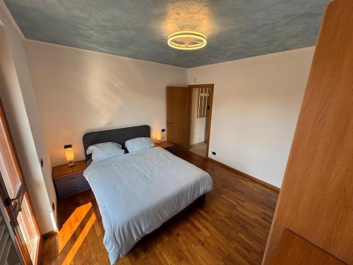 a bedroom with a white bed and a wooden floor at Casa Serena - Sarnico in Sarnico