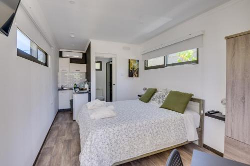 a white bedroom with a bed and a kitchen at THE SPOT GLAMPING STUDIOS PROTARAs in Paralimni