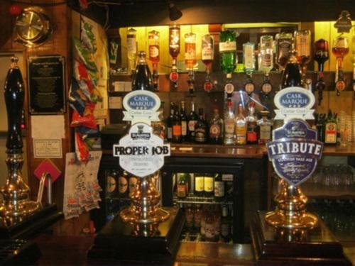 a bar with a counter with bottles of alcohol at The Ship Inn in St Austell