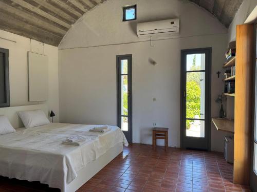 a bedroom with a large white bed and two windows at Ageranos in Vathi