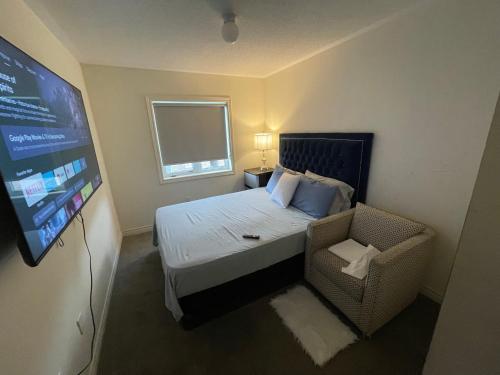 a bedroom with a bed and a tv and a chair at Relax Guest House in Oshawa