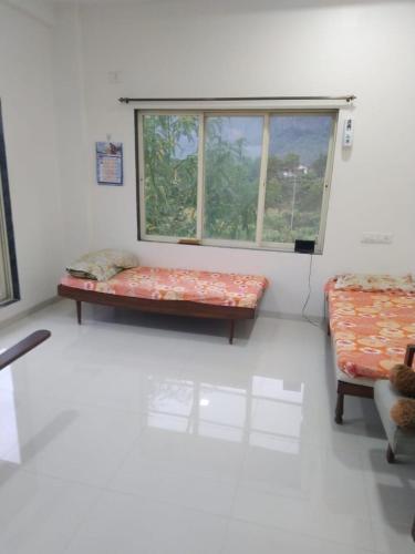 a room with two beds and a window at Shri Bhuvaneshvari Homestay in Karjat