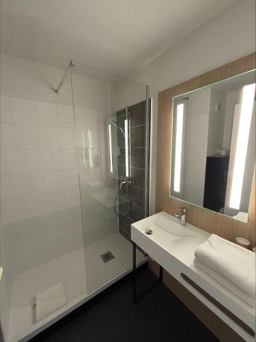a bathroom with a shower and a sink and a mirror at ibis Avallon in Magny