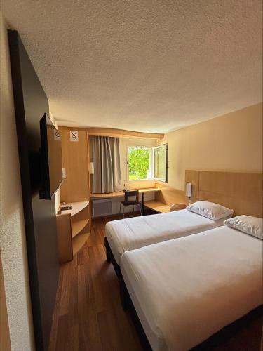 a hotel room with two beds and a desk at ibis Avallon in Magny