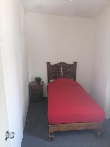 a bedroom with a bed with a red blanket at Hostal Queretaro LOMAS M in Laborcillas