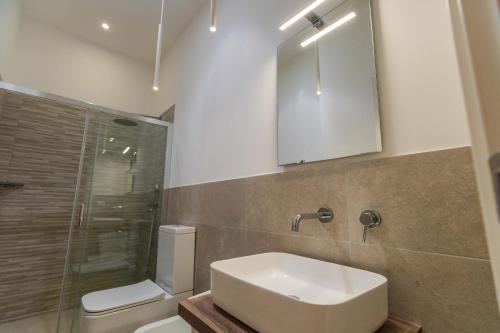 a bathroom with a sink and a toilet and a mirror at La maison de tante Rosa in Syracuse