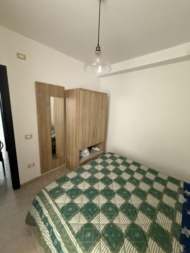 a bedroom with a bed with a green and white quilt at Blue Home in Lampedusa