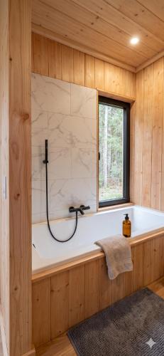 una vasca da bagno in una stanza di legno con una finestra di Stuga a Érezée