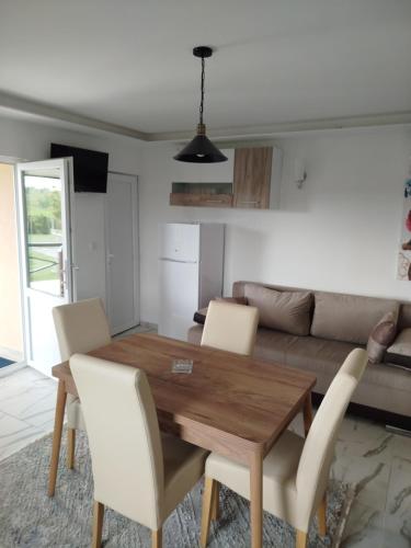 a living room with a wooden table and white chairs at Vikendice Božić in Višnjićevo