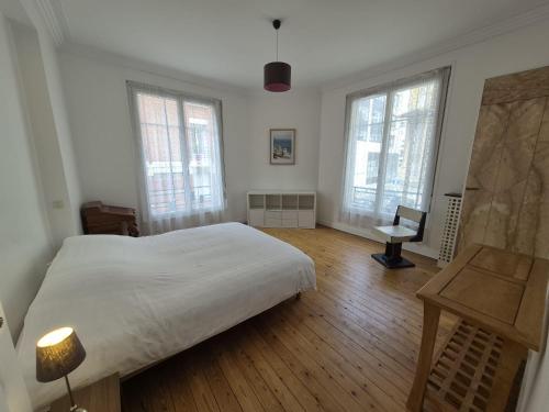 a bedroom with a bed and a desk and windows at LE GATSBY, appartement ART DECO 4 pers, plage et hyper centre in Le Havre