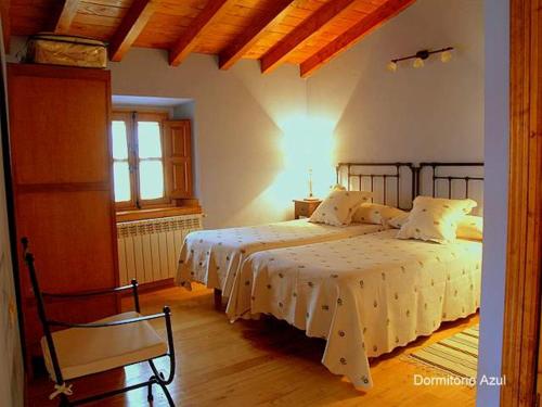 a bedroom with two beds and a chair at Casa de Pamirandi in Asiego