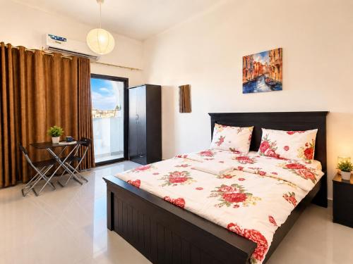 a bedroom with a large bed with red flowers on it at Flora Residence in Abu Dhabi