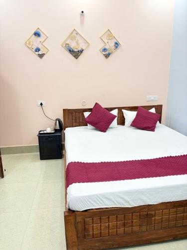 ein Schlafzimmer mit einem Bett mit roten und violetten Kissen in der Unterkunft Hotel Mayaa Inn in Chupra