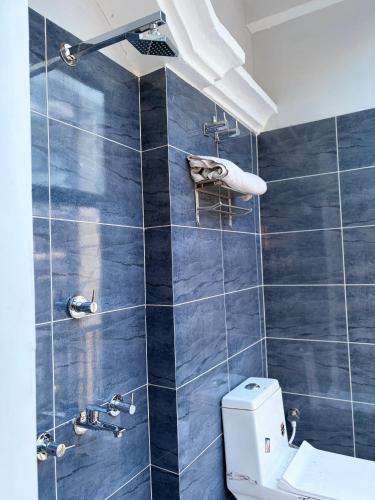 ein Badezimmer mit blau gefliester Wand und einer Toilette in der Unterkunft Hotel Mayaa Inn in Chupra