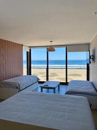 two beds in a room with a view of the beach at Rompe Olas in Maitencillo
