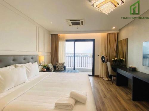 a bedroom with a large white bed and a balcony at Golden Apartment in Da Nang Bay in Danang