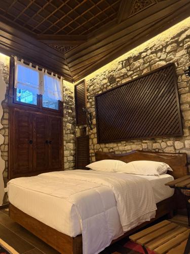 a bedroom with a large bed with a stone wall at Oda e Gurit - Boutique Hotel in Berat