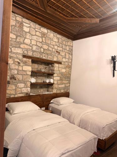 two beds in a room with a stone wall at Oda e Gurit - Boutique Hotel in Berat