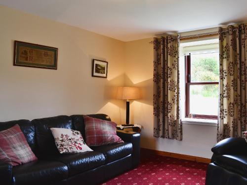 a living room with a black leather couch and a window at Port-An-Eillean in Feorlean