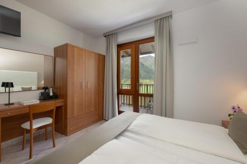 a bedroom with a bed and a desk and a window at Hotel Residence La Pertica in Tremosine Sul Garda