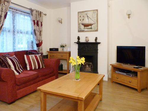 a living room with a couch and a table with a tv at Watchkeeper's Cottage in Mundesley