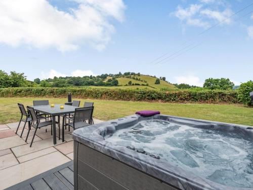 a hot tub on a patio with a table and chairs at Pennant in Llanerfyl