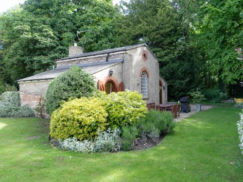 a small brick building with a bench in a yard at Stearn Cottage-17917 in Langham