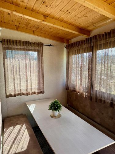 a small room with a table and two windows at Vikendica Varde Žabljak in Žabljak