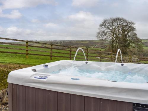 a hot tub in a field next to a fence at Gwel-Y-Lyn in Mydroilin