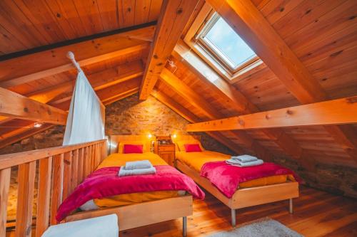 two beds in a attic room with wooden ceilings at La Grange de Cassiopée in Les Angles