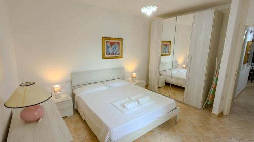 a bedroom with a white bed and a mirror at Gigi's House in Cala Gonone