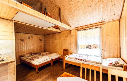 two beds in a room with wooden walls at BiesChatki in Wetlina