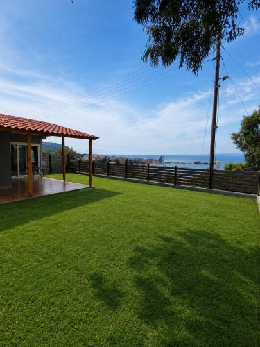 a grassy yard with a fence and a view of the ocean at Ouranoupolis View Point in Ouranoupoli