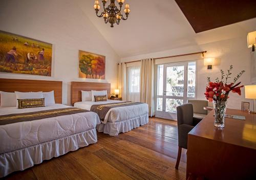 a hotel room with two beds and a table with flowers at Aranwa Pueblito Encantado del Colca in Coporaque