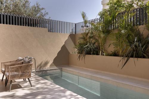 a chair sitting next to a swimming pool with plants at MonCasa suites in Agios Nikolaos