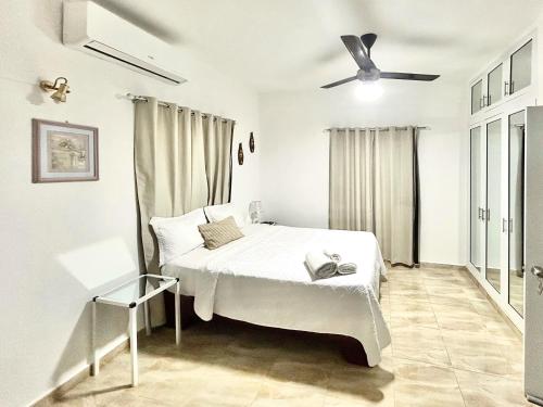 a white bedroom with a bed and a ceiling fan at Mi Refugio 1 in Río San Juan