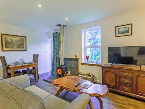 a living room with a couch and a tv and a table at The Bungalow in Dingwall