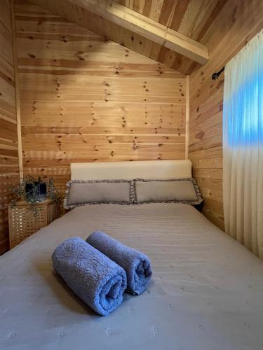 a bed in a wooden cabin with two towels on it at Plava Zora in Kolašin