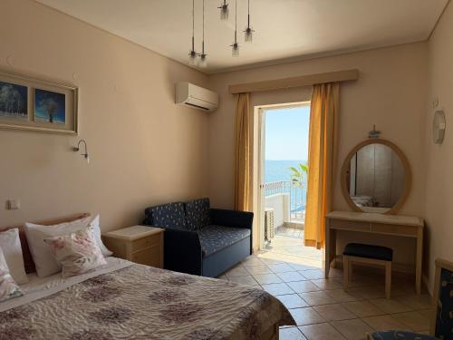 a bedroom with a bed and a chair and a window at Vythos Rooms in Paralio Astros