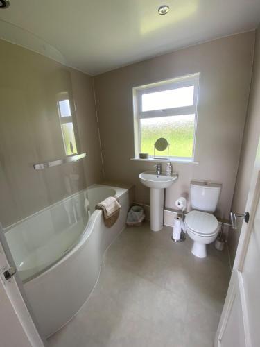 a bathroom with a tub and a toilet and a sink at 1 Shawsmuir Cottage in Thornhill
