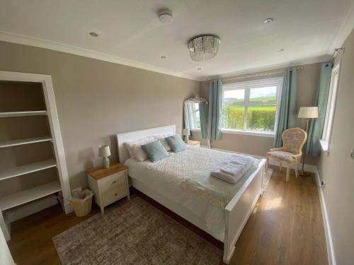 a bedroom with a bed and a chair and a window at 1 Shawsmuir Cottage in Thornhill