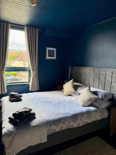 a bedroom with a bed with blue walls and a window at 15 By The Shore in Caol