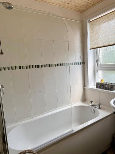 a white bath tub in a bathroom with a window at 15 By The Shore in Caol