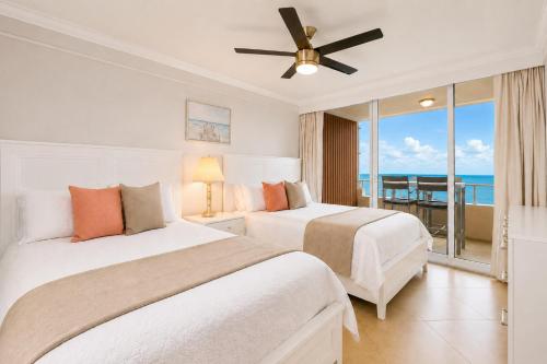 two beds in a bedroom with a view of the ocean at Beachfront Condo with Pool, Balcony & Ocean Views in Fort Lauderdale