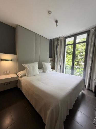 a bedroom with a large white bed with a large window at Hotel Avenida 31 in Marbella