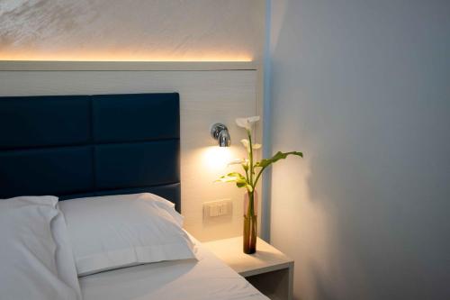 a bedroom with a bed with a vase with a flower at Hotel Villa Irene & Spa in Rimini